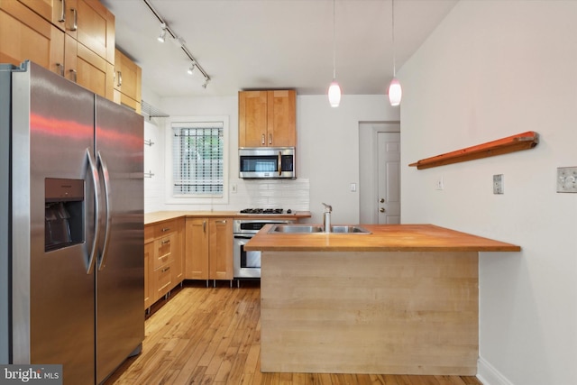 kitchen featuring wooden counters, sink, light wood-type flooring, appliances with stainless steel finishes, and decorative light fixtures