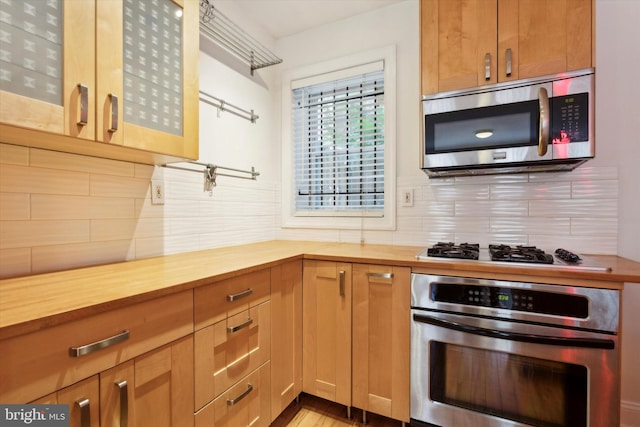 kitchen featuring wooden counters, backsplash, and stainless steel appliances