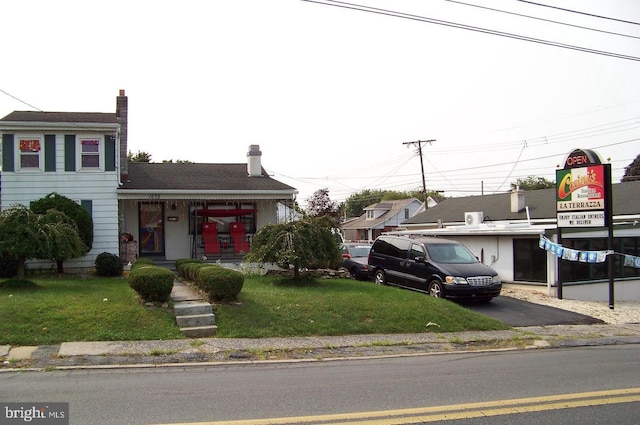 view of front of home featuring a front yard, covered porch, and aphalt driveway