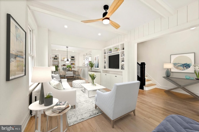 living room featuring light hardwood / wood-style flooring, ceiling fan, and beamed ceiling