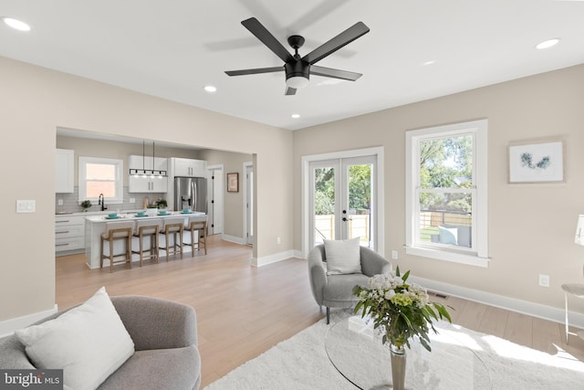 living room featuring sink, light wood-type flooring, and ceiling fan