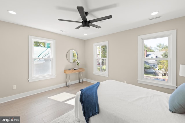 bedroom featuring light wood-type flooring, multiple windows, and ceiling fan