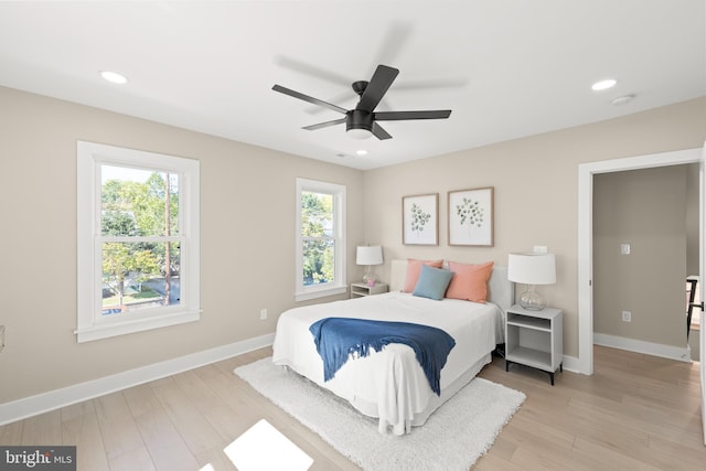 bedroom with ceiling fan, light hardwood / wood-style floors, and multiple windows