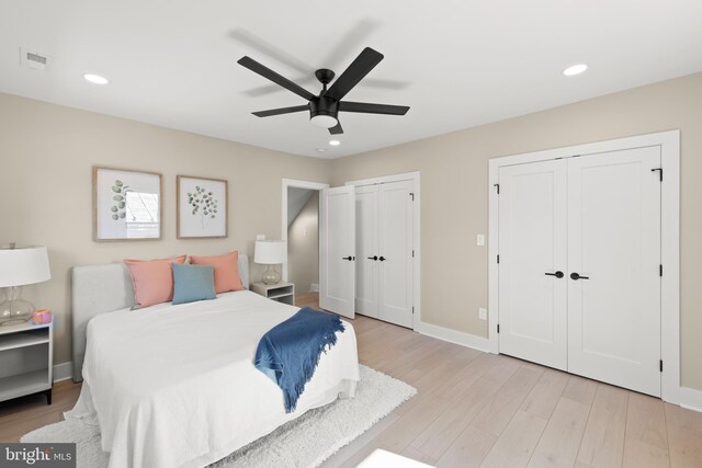 bedroom featuring multiple closets, light wood-type flooring, and ceiling fan