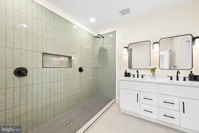 bathroom with tile patterned floors, a tile shower, and vanity