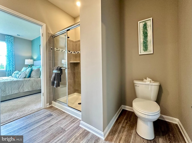 bathroom with wood-type flooring, walk in shower, and toilet