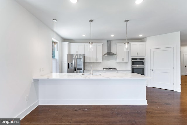 kitchen featuring pendant lighting, sink, wall chimney range hood, white cabinetry, and stainless steel appliances