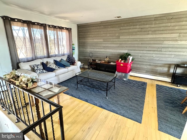 living room featuring hardwood / wood-style flooring, a baseboard heating unit, and wood walls