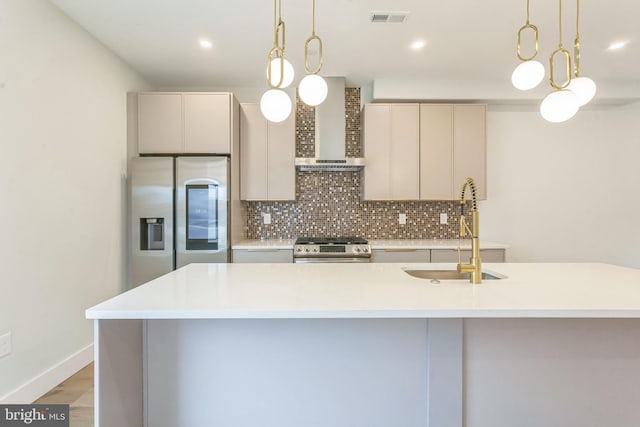 kitchen with wall chimney exhaust hood, stainless steel appliances, sink, and pendant lighting