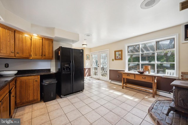 kitchen featuring light tile patterned floors, baseboard heating, and black refrigerator with ice dispenser