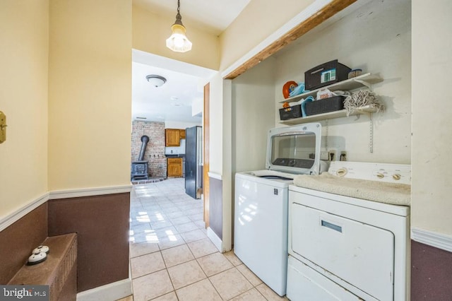 bar with washing machine and clothes dryer, a wood stove, hanging light fixtures, light tile patterned floors, and stainless steel fridge