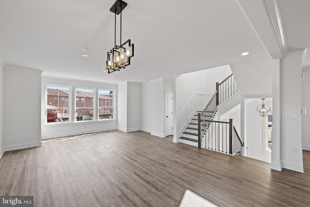 unfurnished living room with crown molding, hardwood / wood-style floors, and a chandelier