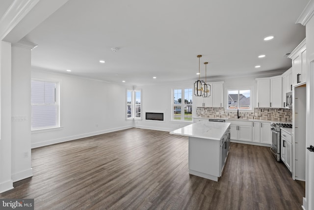 kitchen with light stone countertops, decorative light fixtures, a kitchen island, white cabinetry, and stainless steel range with gas stovetop