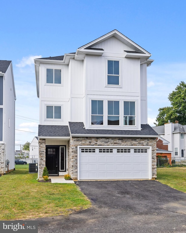 view of front of house with a front yard, a garage, and central air condition unit