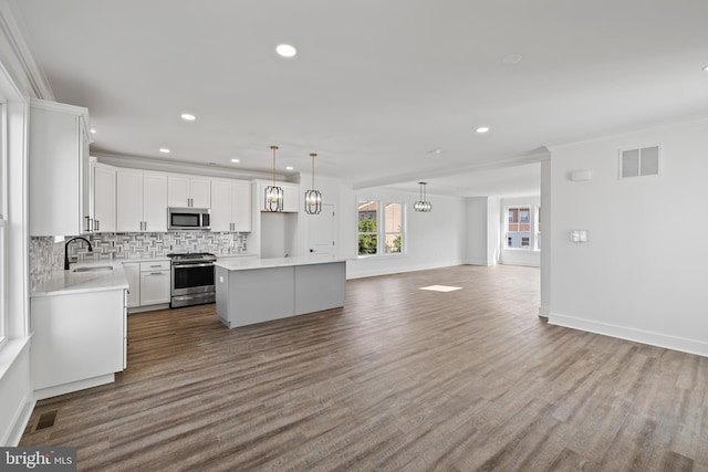 kitchen with decorative backsplash, stainless steel appliances, sink, white cabinets, and a center island