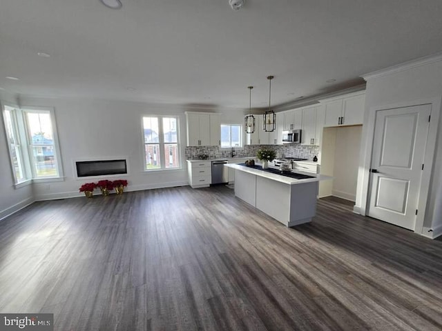 kitchen featuring white cabinetry, a kitchen island, stainless steel appliances, and decorative light fixtures