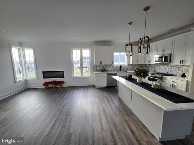 kitchen with white cabinets, decorative light fixtures, a wealth of natural light, and appliances with stainless steel finishes