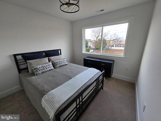 bedroom featuring dark colored carpet and multiple windows