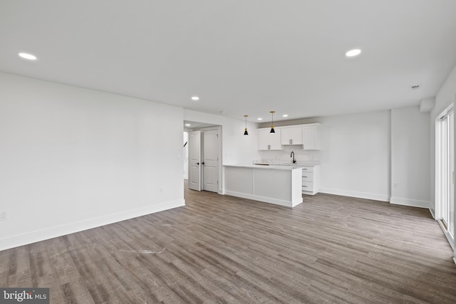 unfurnished living room featuring sink and hardwood / wood-style floors