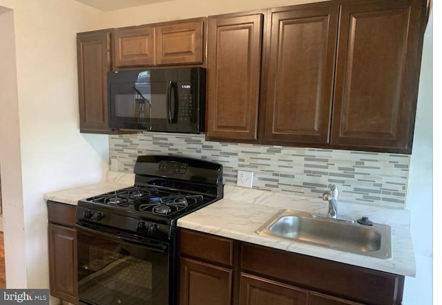 kitchen with dark brown cabinets, black appliances, tasteful backsplash, and sink