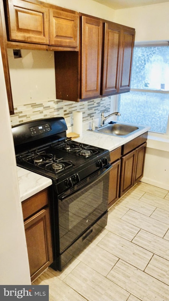 kitchen featuring backsplash, black range with gas cooktop, and sink