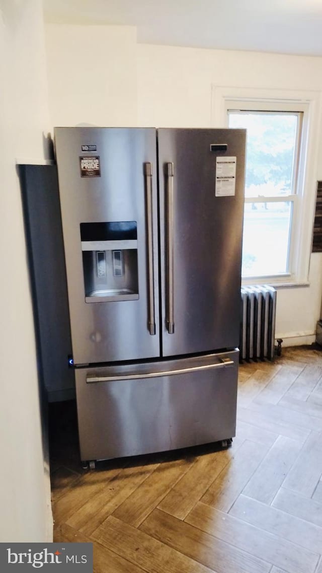 room details with radiator, stainless steel refrigerator with ice dispenser, and light parquet flooring