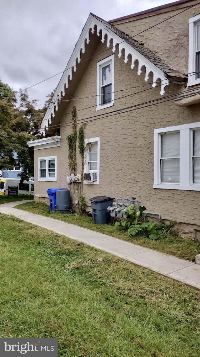 view of side of property featuring cooling unit and a yard