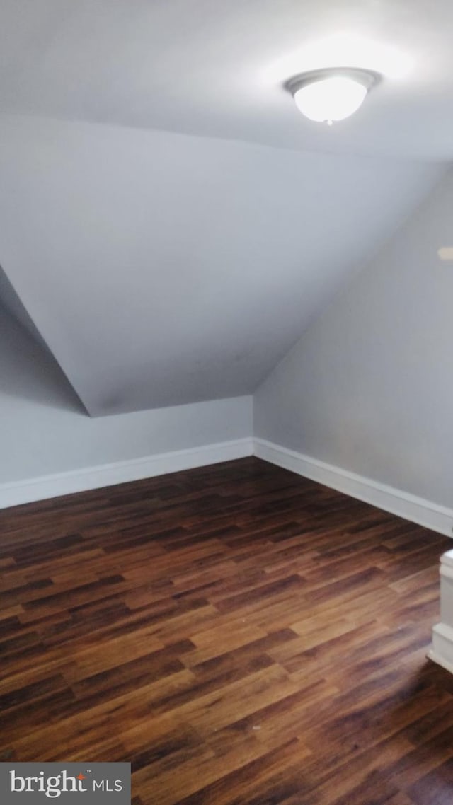 bonus room featuring vaulted ceiling and dark wood-type flooring