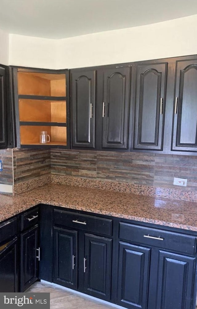 kitchen featuring backsplash, light hardwood / wood-style floors, and stone countertops