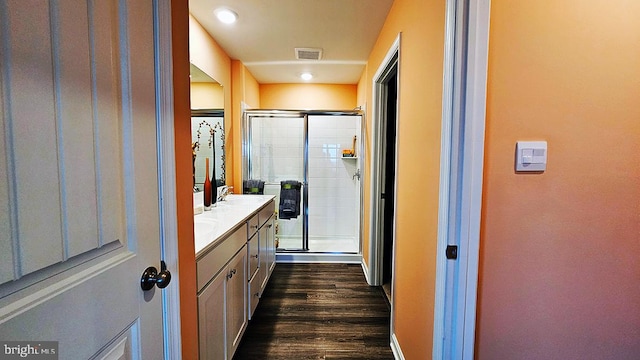 bathroom with hardwood / wood-style floors, walk in shower, and vanity