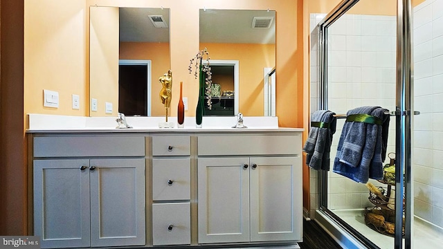 bathroom featuring a shower with shower door and vanity