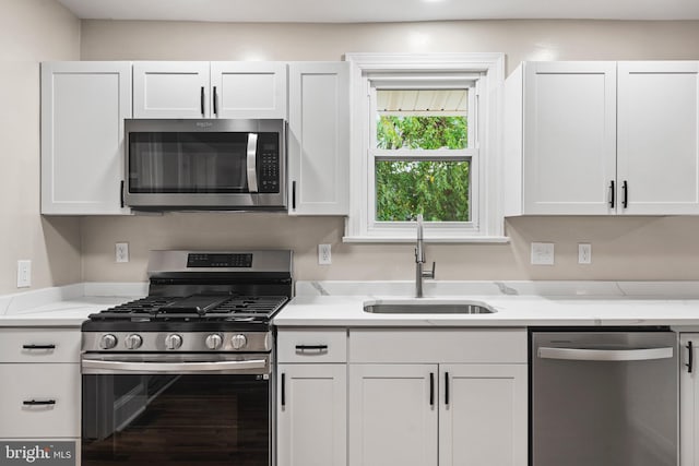 kitchen featuring appliances with stainless steel finishes, white cabinets, and sink