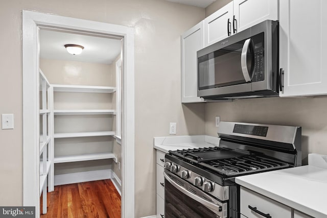 kitchen with white cabinets, stainless steel appliances, and dark hardwood / wood-style floors