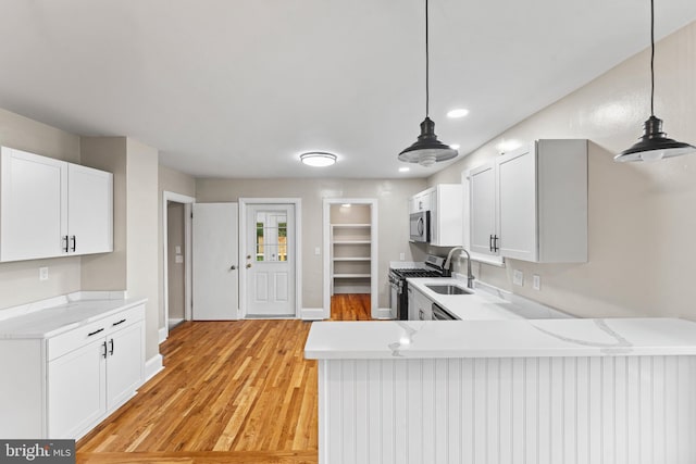 kitchen featuring appliances with stainless steel finishes, kitchen peninsula, pendant lighting, and white cabinetry