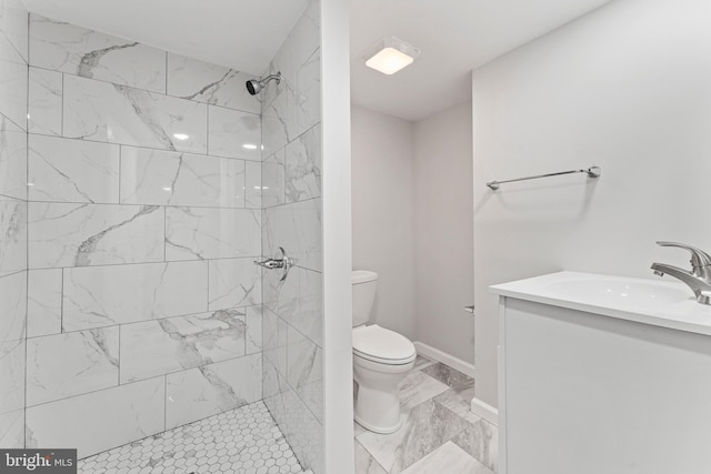 bathroom featuring toilet, vanity, and a tile shower