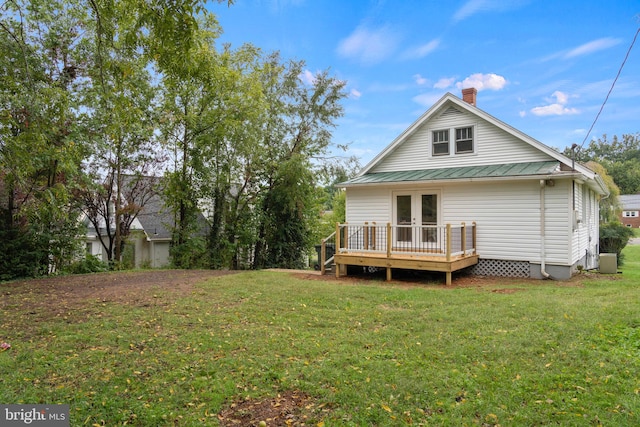 rear view of property featuring a wooden deck and a lawn