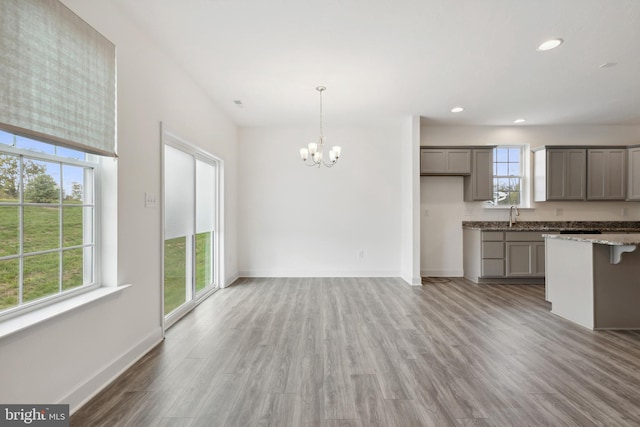 kitchen with a wealth of natural light, gray cabinets, a chandelier, and light wood finished floors