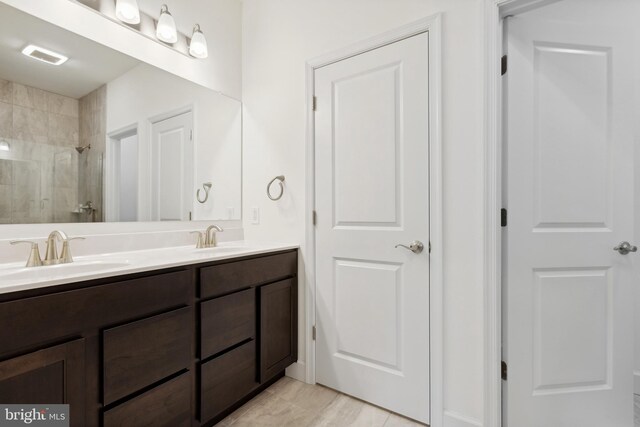 full bath with double vanity, visible vents, a sink, and a tile shower