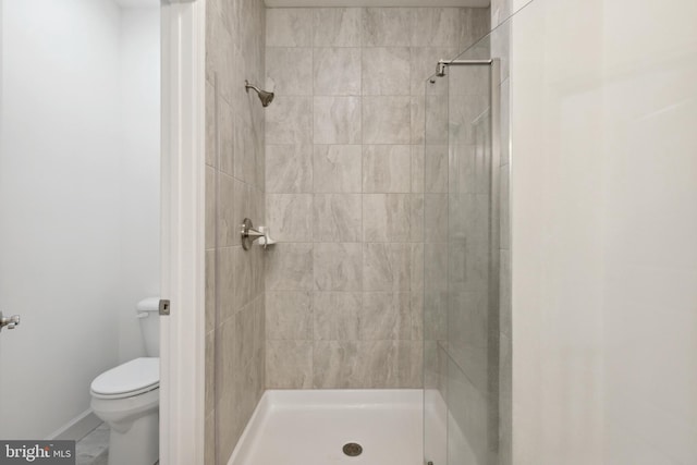 bathroom with toilet, baseboards, and a shower stall