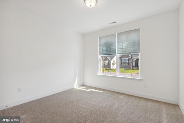 carpeted spare room featuring baseboards and visible vents
