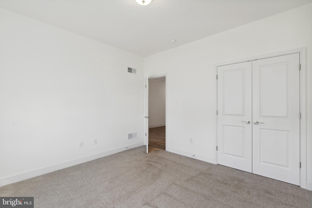 unfurnished bedroom featuring baseboards, carpet, a closet, and visible vents