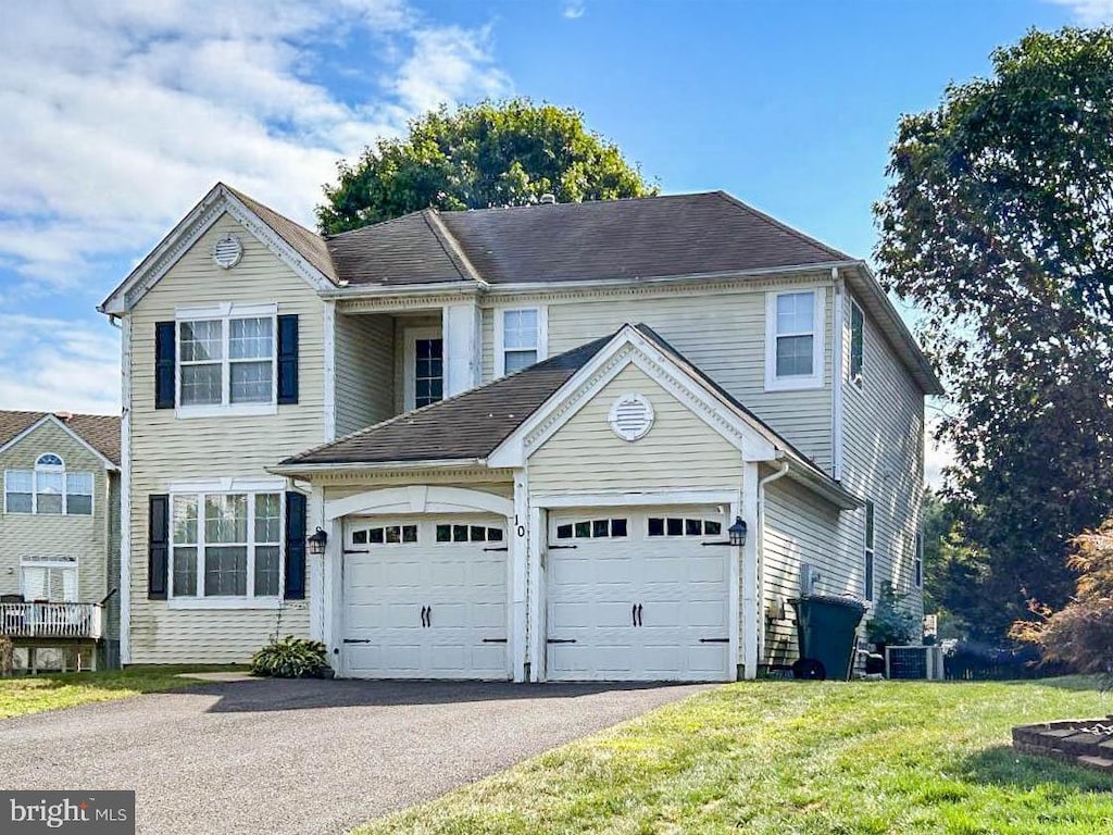 front of property featuring a front yard, a garage, and central air condition unit