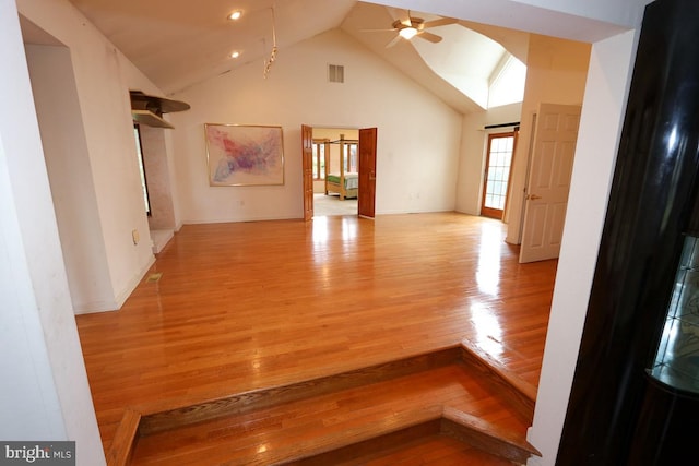 unfurnished living room featuring high vaulted ceiling, light hardwood / wood-style floors, and ceiling fan