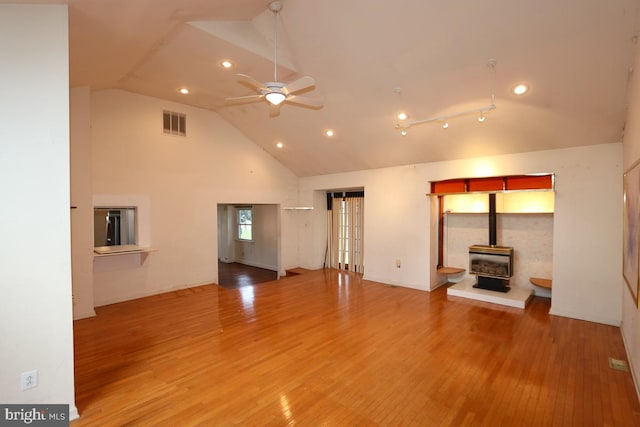 unfurnished living room featuring high vaulted ceiling, a wood stove, ceiling fan, and hardwood / wood-style flooring