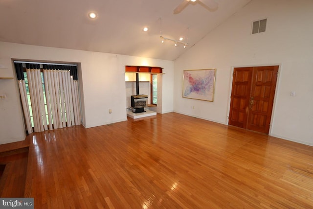 unfurnished living room featuring light wood-type flooring, a wood stove, and a wealth of natural light