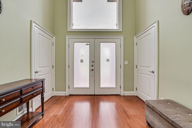 entryway featuring light wood-type flooring, a high ceiling, and french doors