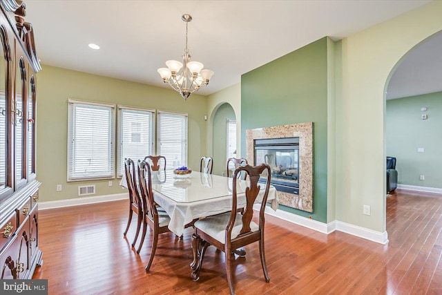 dining space with a high end fireplace, light hardwood / wood-style flooring, and a chandelier