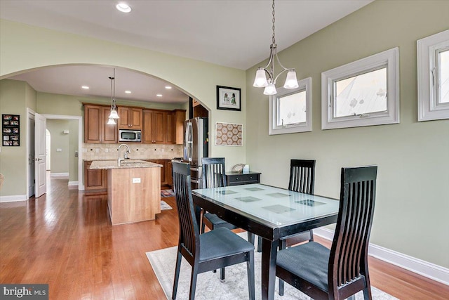 dining area with an inviting chandelier, hardwood / wood-style floors, and sink