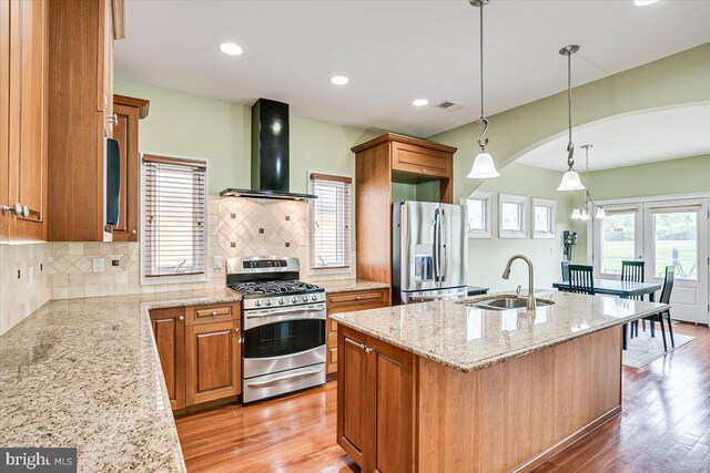 kitchen featuring sink, a center island with sink, extractor fan, stainless steel appliances, and light hardwood / wood-style floors