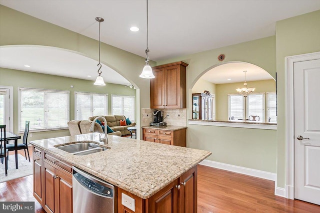 kitchen with light hardwood / wood-style floors, a center island with sink, stainless steel dishwasher, sink, and a chandelier